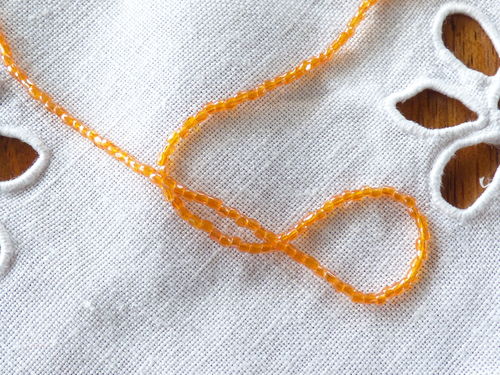 Perles rocaille sur fil col orange clair